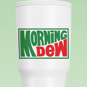 May include: A white tumbler with the words "MORNING DEW" in green and red lettering. The text is inside a green rectangle. The tumbler is cylindrical with a slightly flared base and a white lid.