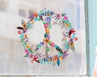 May include: A peace sign sticker with a floral design in shades of pink, purple, blue, yellow, and green. The sticker is on a window with a light blue frame.