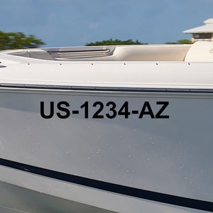 May include: Close-up of a white boat with a black stripe and the registration number US-1234-AZ on the side.