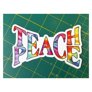 Another view of the 'Teach Peace sticker' next to a ruler to confirm its size, ideal for precise placement.