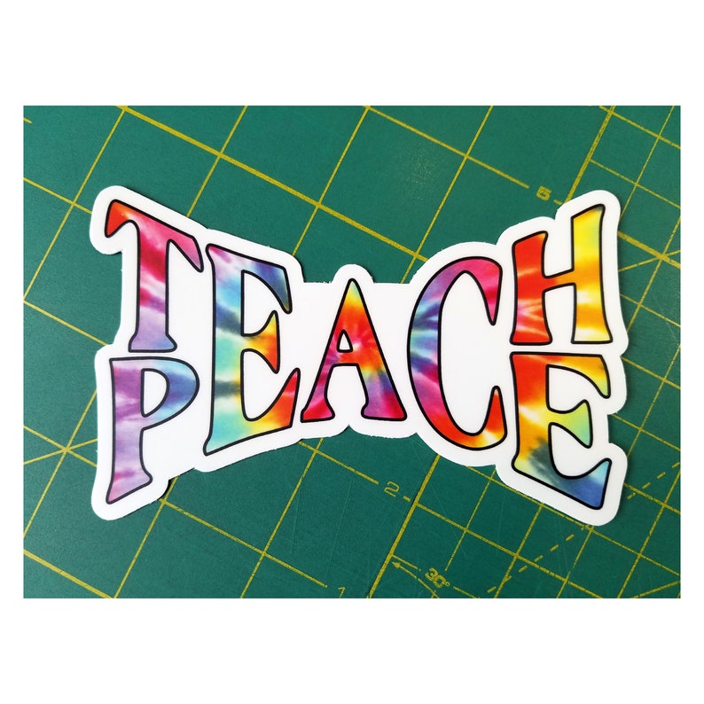 Another view of the 'Teach Peace sticker' next to a ruler to confirm its size, ideal for precise placement.