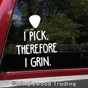 May include: White vinyl sticker on a red car window. The sticker features a guitar pick shape and the text "I PICK, THEREFORE I GRIN."  The text "©Minglewood Trading" is at the bottom of the sticker.