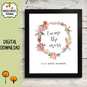 May include: Black framed print with a floral wreath design. The wreath surrounds the text "Excuse the mess" and "I'm a shitty housewife.". The print is a digital download from Minglewood Trading.