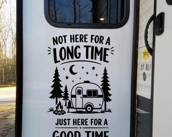 May include: A black vinyl decal applied to a white camper door featuring the text NOT HERE FOR A LONG TIME and JUST HERE FOR A GOOD TIME. The design includes a graphic of a vintage travel trailer, pine trees, a campfire, and a crescent moon.