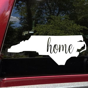 May include: White vinyl decal of the state of North Carolina with the word "home" written in cursive inside the outline of the state.