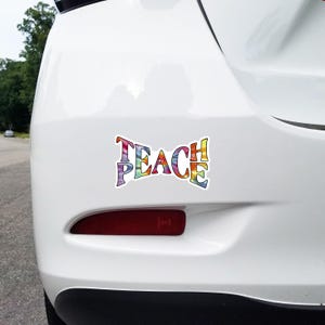 Teach Peace sticker adhered to the rear bumper of a car, showcasing how it beautifies and sends a positive message on the road.
