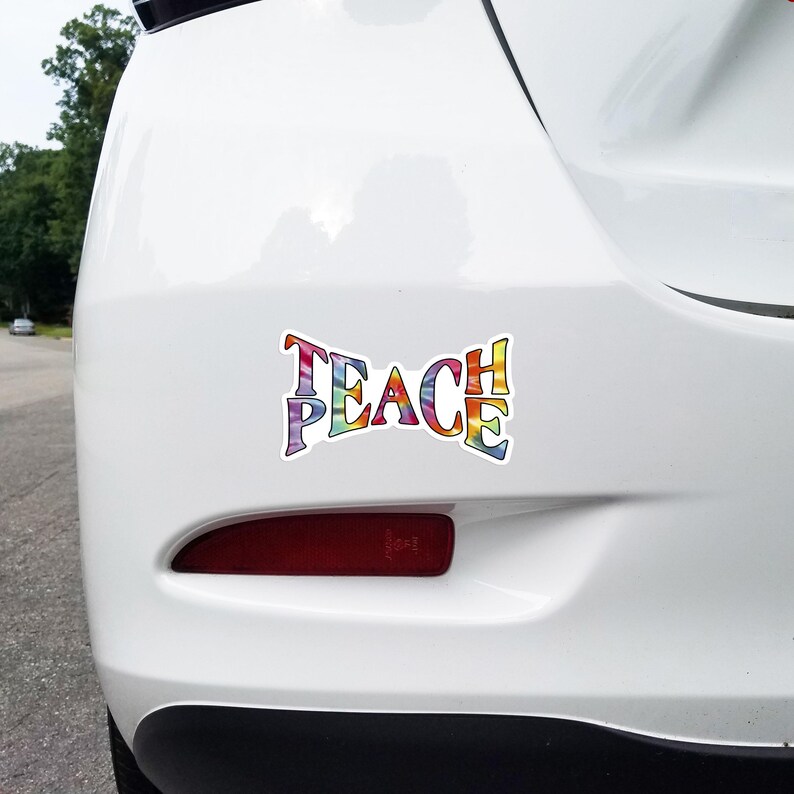 Teach Peace sticker adhered to the rear bumper of a car, showcasing how it beautifies and sends a positive message on the road.