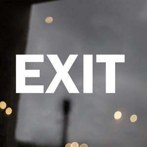 May include: White "EXIT" sign on a glass door with a blurry background of lights.
