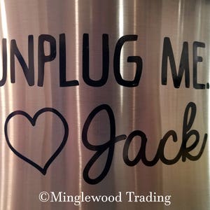 May include: Stainless steel tumbler with a black vinyl decal that reads "Unplug Me... Jack" with a heart symbol. The decal is on a silver background. The bottom of the tumbler has the text "Minglewood Trading".