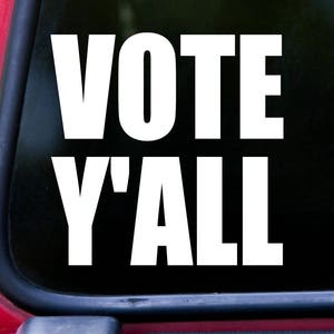 May include: White vinyl decal with the text "VOTE Y'ALL" in bold, block letters. The decal is on a black background.