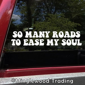 May include: White vinyl decal with the text "So many roads to ease my soul" in a retro font style. The decal is applied to the back window of a red truck.