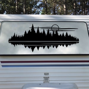 May include: A black silhouette of a forest with a full moon and reflection in a lake. The image is on a white camper trailer.