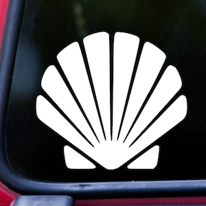 May include: White vinyl decal of a seashell. The seashell is a simple design with a rounded shape and multiple lines radiating from the center.
