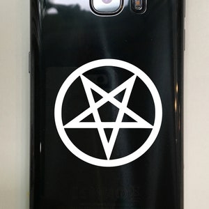 Puede incluir: Un tel&eacute;fono inteligente negro con una pegatina de pentagrama blanco en la parte posterior.