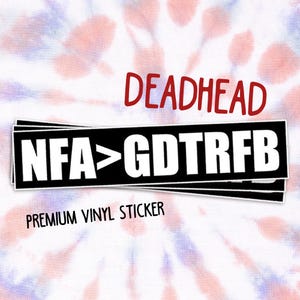 May include: A premium vinyl sticker with the word "DEADHEAD" in red, above a black and white rectangular design with the text "NFA > GDTRFB". The background has a tie-dye pattern in shades of red, white, and blue.