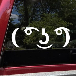 May include: White vinyl sticker of a smiley face with the number 5 in the middle of the face. The sticker is on the back window of a car.