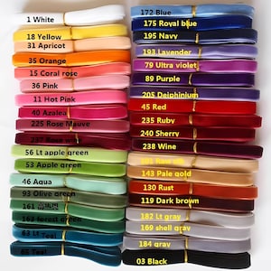 May include: A selection of velvet ribbons in a spectrum of colours, such as white, yellow, orange, pink, green, blue, and purple. Each ribbon is labelled with a number and colour name. The ribbons are neatly stacked, displaying a wide range of shades.