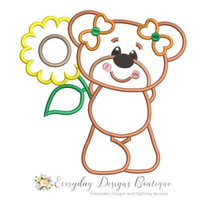 Könnte beinhalten: Ein brauner Teddybär mit grünen Schleifen, der eine gelbe Sonnenblume mit grünem Stiel und Blatt hält. Der Bär hat eine rosa Nase und Wangen.