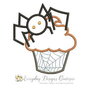 May include: Black and white embroidery design of a spider on top of a cupcake with a web design. The cupcake is orange and the web is green.