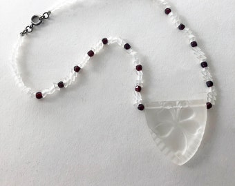 May include: A white glass necklace with a carved flower pendant and red glass beads.