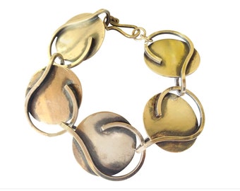 May include: A gold-toned bracelet with a unique design featuring interlocking circular links. Each link has a curved, organic shape and a smooth, polished finish.
