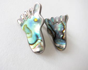 May include: A pair of silver earrings shaped like feet, with iridescent abalone shell inlays.
