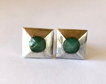 May include: A pair of silver earrings with a square shape and a green stone in the center.