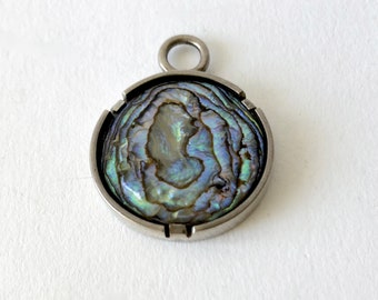 May include: A silver pendant with a round abalone shell inlay. The shell has a swirling pattern of iridescent blue, green, and purple.