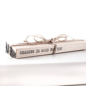 May include: A stack of books tied together with twine and a metal bookend. The top book has the text "Reading is good for you" printed on it.