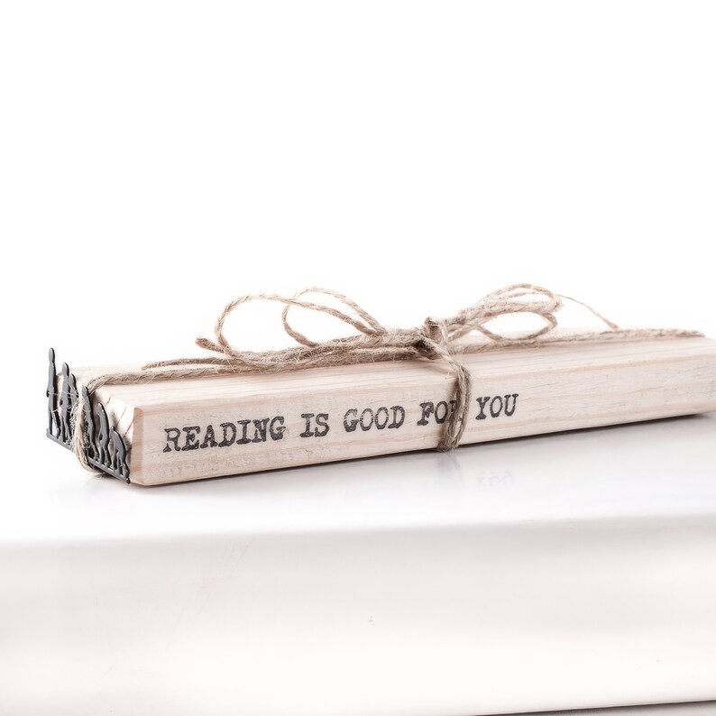 May include: A stack of books tied together with twine and a metal bookend. The top book has the text "Reading is good for you" printed on it.