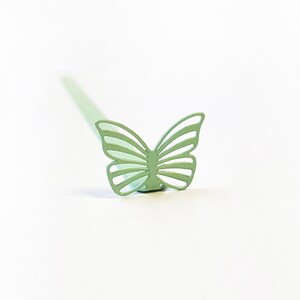 May include: A light green metal butterfly shaped cocktail stirrer.