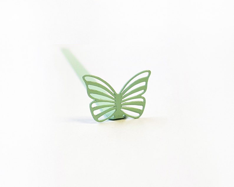 May include: A light green metal butterfly shaped cocktail stirrer.