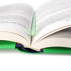 May include: A green book with a light green butterfly bookmark. The book is open to page 253.
