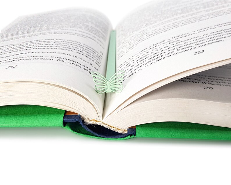 May include: A green book with a light green butterfly bookmark. The book is open to page 253.