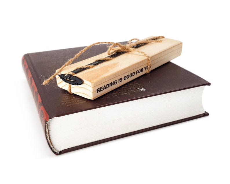 May include: A brown hardcover book with a wooden bookmark. The bookmark is tied with twine and has a feather design. The bookmark has the text "Reading is good for you".
