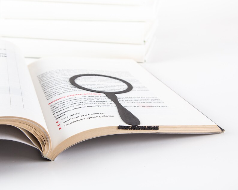 Black metal bookmark Magnifying Glass in the book. The writing on the side says Seek Knowledge.