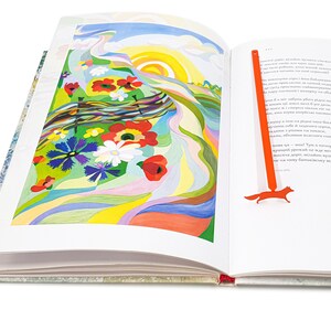 May include: An open book with a colorful illustration of a field of flowers and a bright sun. A red fox bookmark is on the right page.