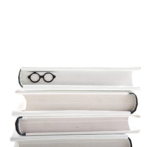 Architect-inspired black metal page saver shaped like Bauhaus-style round glasses, subtly tucked into a stacked set of white hardcovers. A minimalist tribute to modern design and reading culture