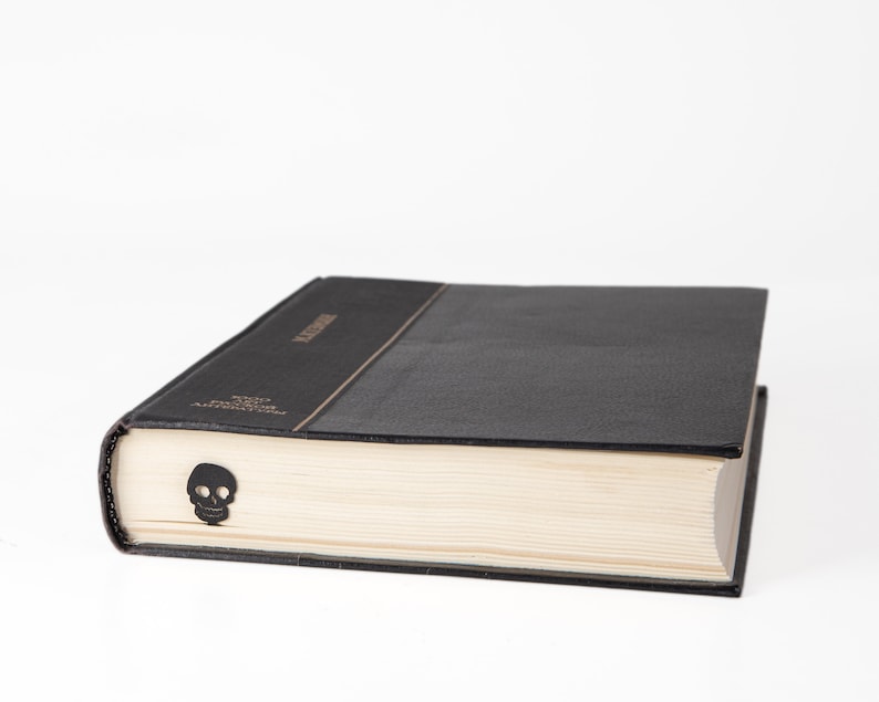 Black metal bookmark. A flat metal stic is between the pages of the book. The black skull is on the side of the book. It is seen even when the book is closed. Made by us in Cherkasy, Ukraine. Not mass manufactured.