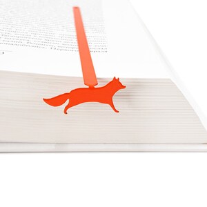 May include: Orange fox bookmark for a book. The bookmark is made of metal and is shaped like a fox.