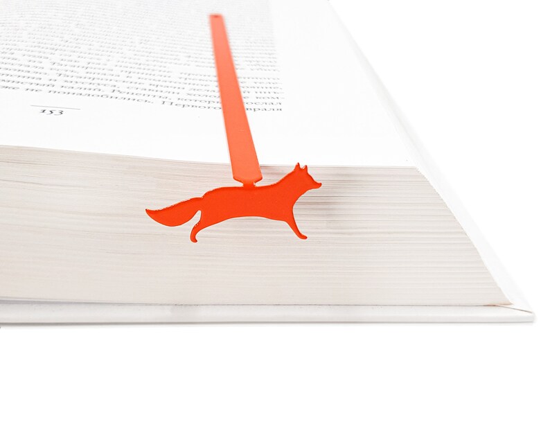 May include: Orange fox bookmark for a book. The bookmark is made of metal and is shaped like a fox.