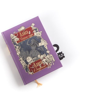 Black metal bookmark Cheshire Cat. The cat is visible on the shelf when the book divider is put in between the books - Coolbookmark.