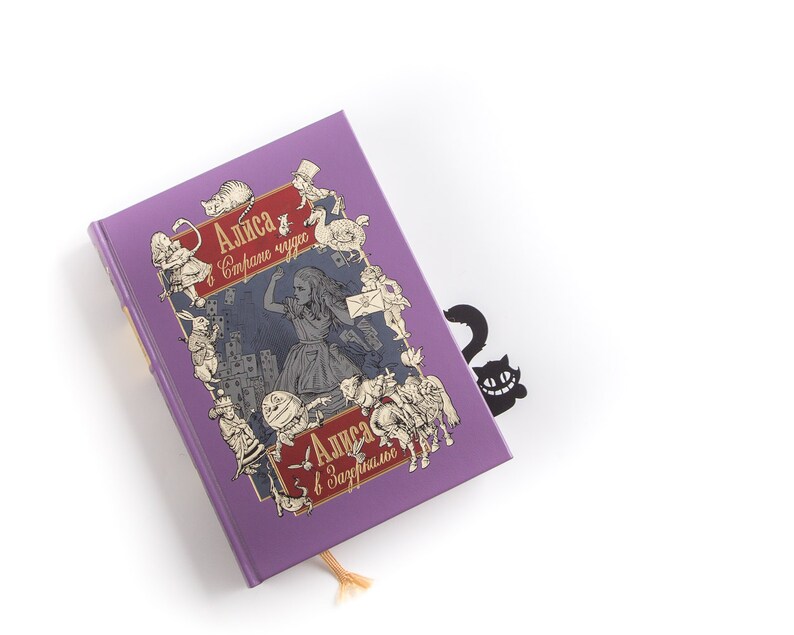 Black metal bookmark Cheshire Cat. The cat is visible on the shelf when the book divider is put in between the books - Coolbookmark.