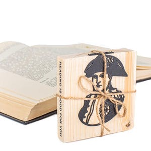 Könnte beinhalten: Buchstützen aus Holz mit einer Silhouette einer Person mit Hut und dem Text "Reading is good for you".