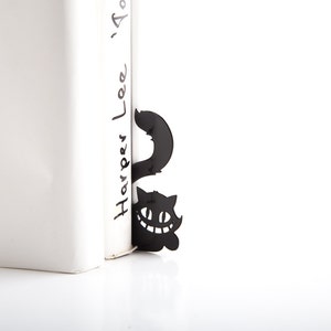 Black metal bookmark Cheshire Cat. The cat is visible on the shelf when the book divider is put in between the books - Coolbookmark.