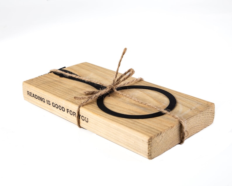 Black metal bookmark Magnifying Glass fastened to the wooden block. The writing says Reading is Good for You.