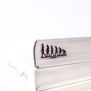 May include: A stack of white books with a black evolution bookmark on the top book.