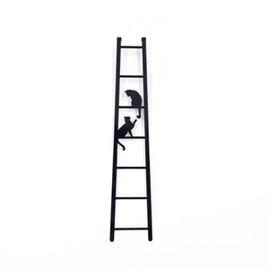 Black metal bookmark shaped like a ladder with two cats climbing, minimalist silhouette design on a white background.