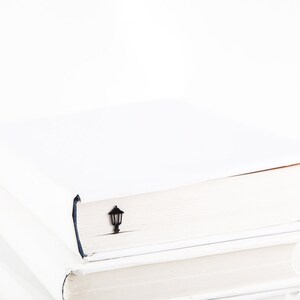 Black metal bookmark Lamppost. A flat metal stick in the shape of a lampost stays between the pages of the book. The lantern is on the side of the book.  It is visible even when the book is closed. Made in Ukraine. Not mass manufactured.