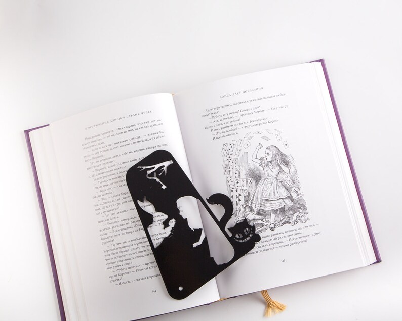 Black metal bookmark Cheshire Cat. The cat is visible on the shelf when the book divider is put in between the books - Coolbookmark.